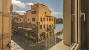 A view from a window overlooking a street with buildings and a body of water. - Stunning Apartment with Ponte Vecchio and Arno River Views
 (Firenze)