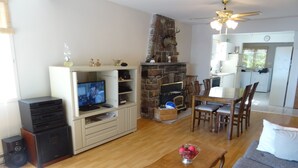Una sala de estar con chimenea, muebles de madera, un televisor y un comedor.