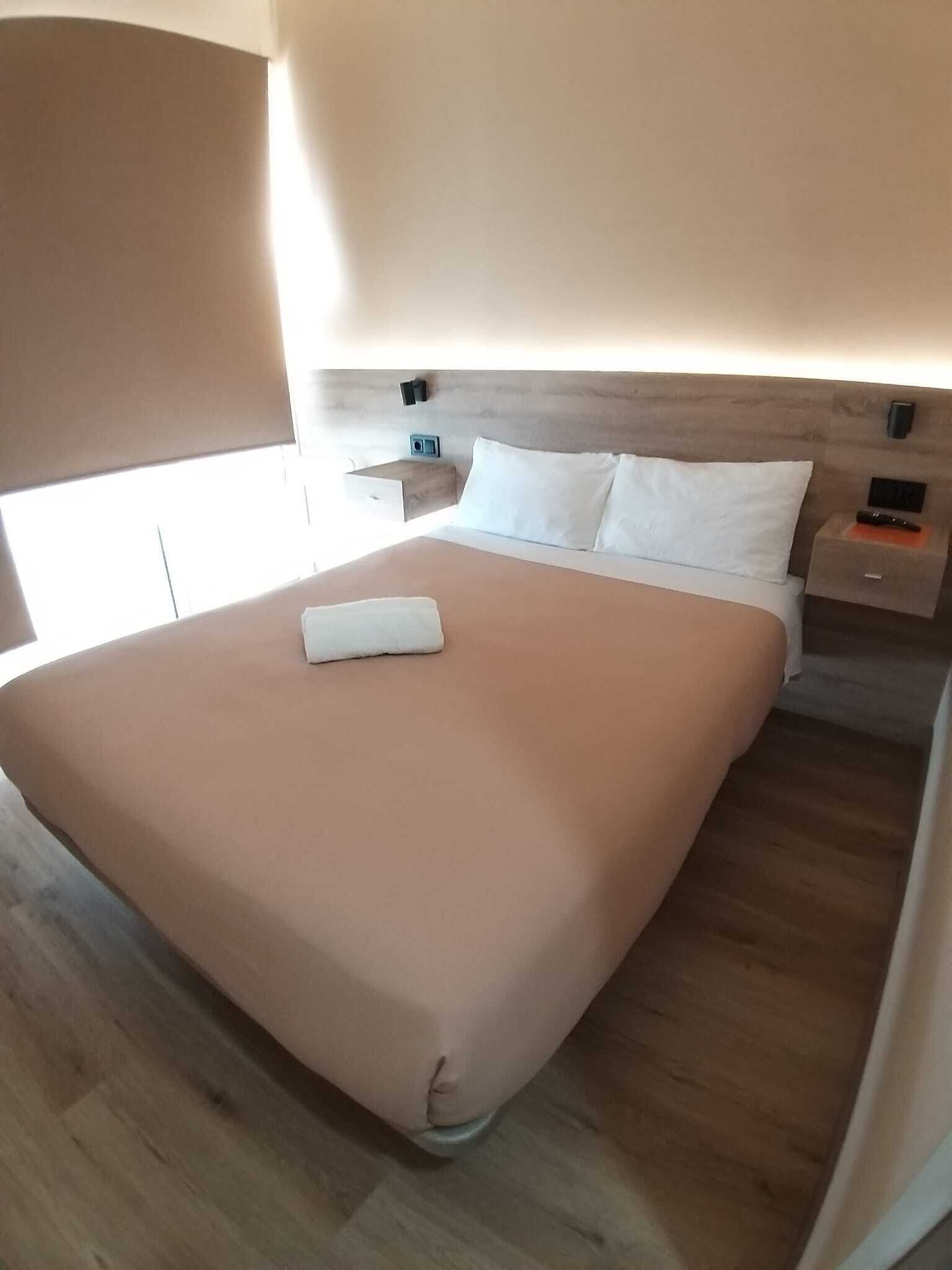 Una habitación de hotel moderna con una cama grande, una mesita de noche y una mesilla.
