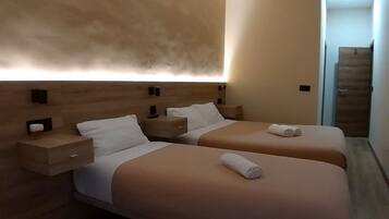 Una habitación de hotel moderna con dos camas, cabeceros de madera y mesitas de noche.