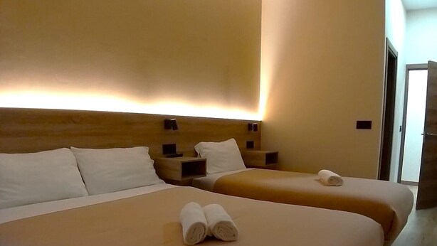 Een hotelkamer met twee bedden, elk met hoofdeinde en nachtkastjes.