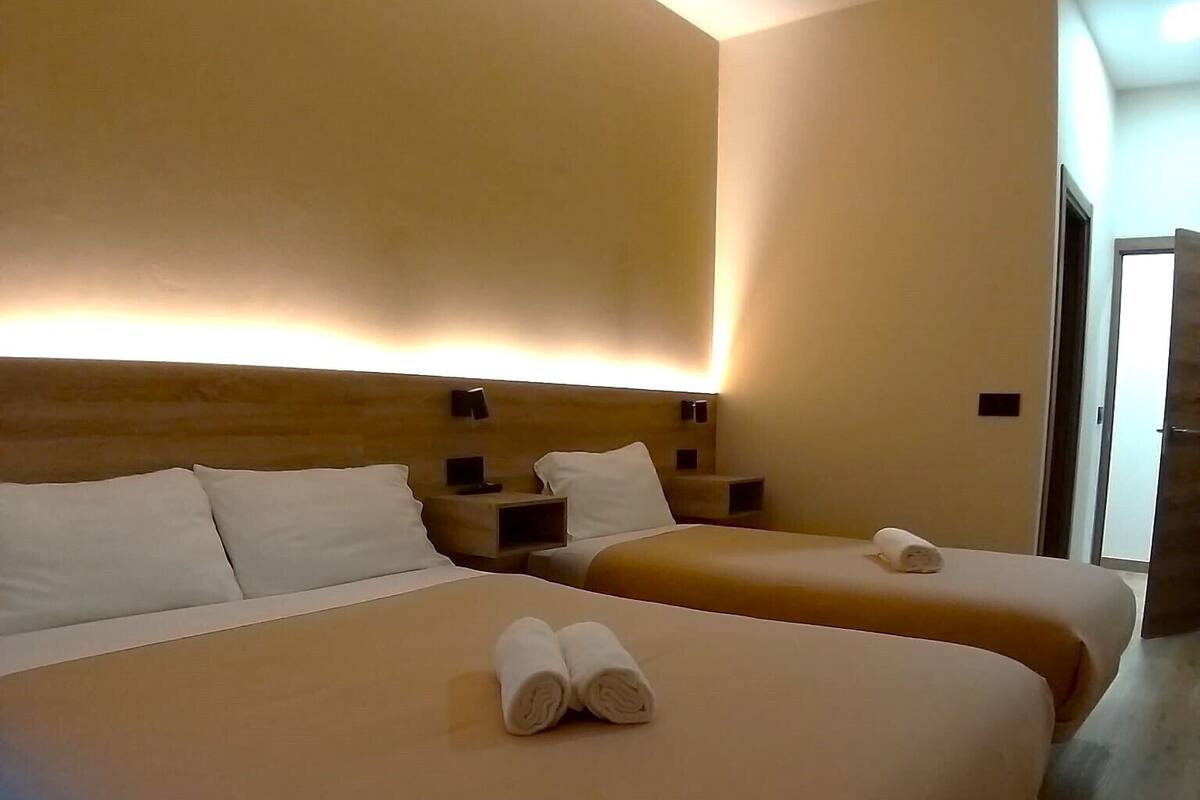 Une chambre d’hôtel avec deux lits, chacun doté d’une tête de lit et de tables de chevet.