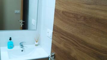 Un baño con un lavamanos blanco, un espejo y armarios de madera.