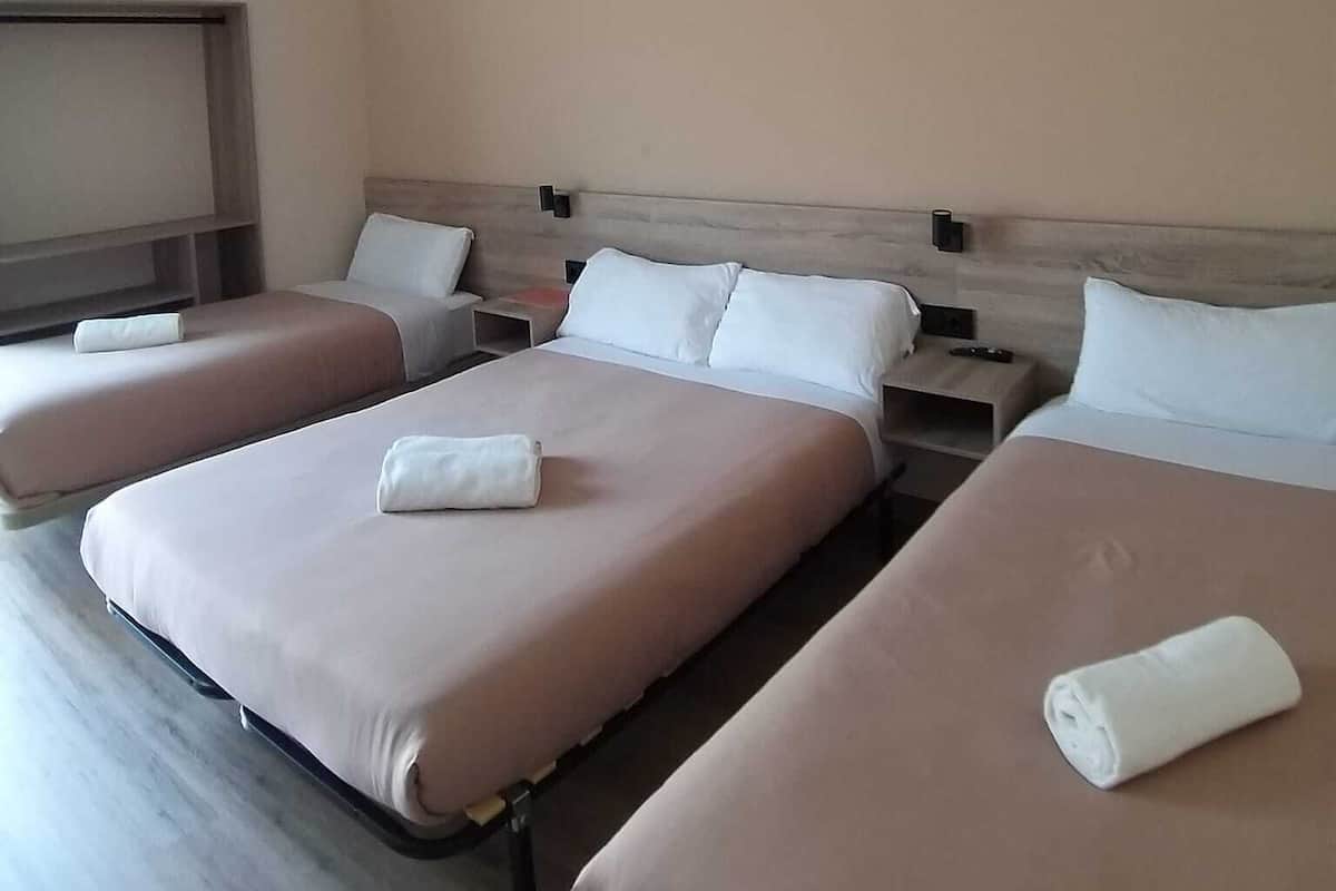 Une chambre d’hôtel avec trois lits, chacun étant équipé d’un oreiller et d’une serviette roulée.