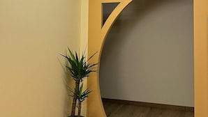Een hal met een moderne lamp, een groot boogvormig portaal en een potplant.