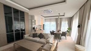 A modern living room with a sofa, coffee table, and dining area. - Deluxe Kamala pool villa with maid (Kamala)