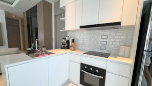 A modern kitchen with white cabinetry, a built-in oven, and a coffee machine. - Deluxe Kamala pool villa with maid (Kamala)