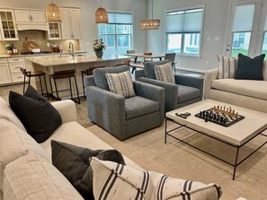 A modern living room with a sofa, armchairs, a coffee table, and a chessboard.
