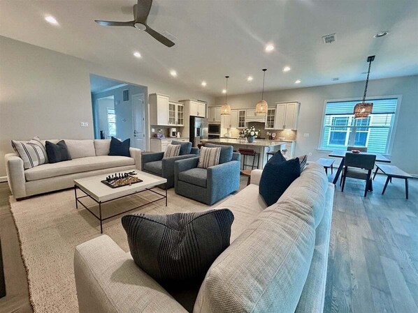 A spacious living room with a sofa set, a coffee table, and a dining area with a table and chairs.