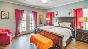 Un dormitorio con una cama grande, un banco, una silla y un ventilador de techo.