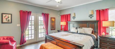 Ein Schlafzimmer mit einem großen Bett, einer Bank, einem Sessel und einem Deckenventilator.