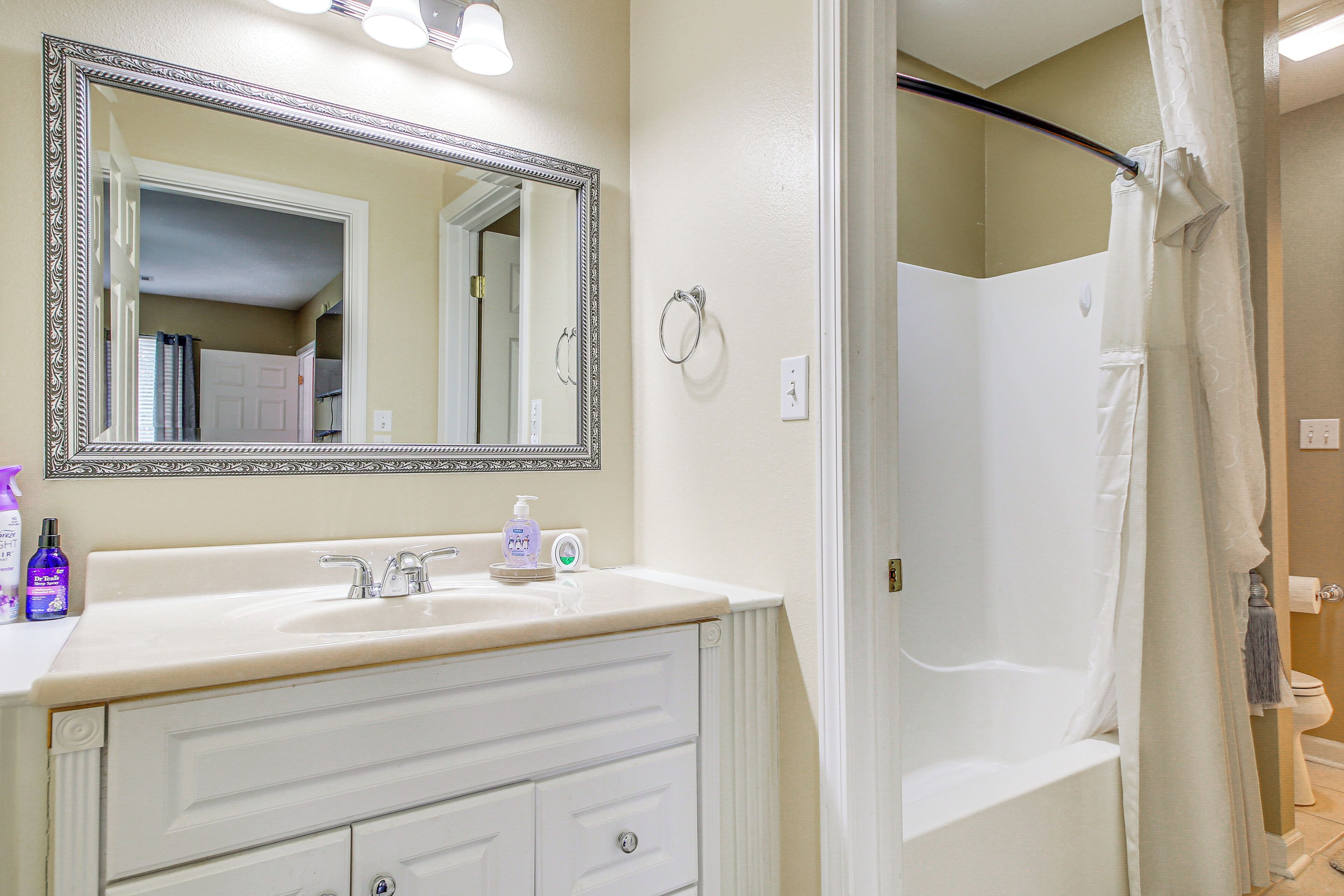 A bathroom with a white sink, mirror, and bathtub.