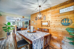 Un'area pranzo in legno con un tavolo apparecchiato per quattro, circondato da sedie.