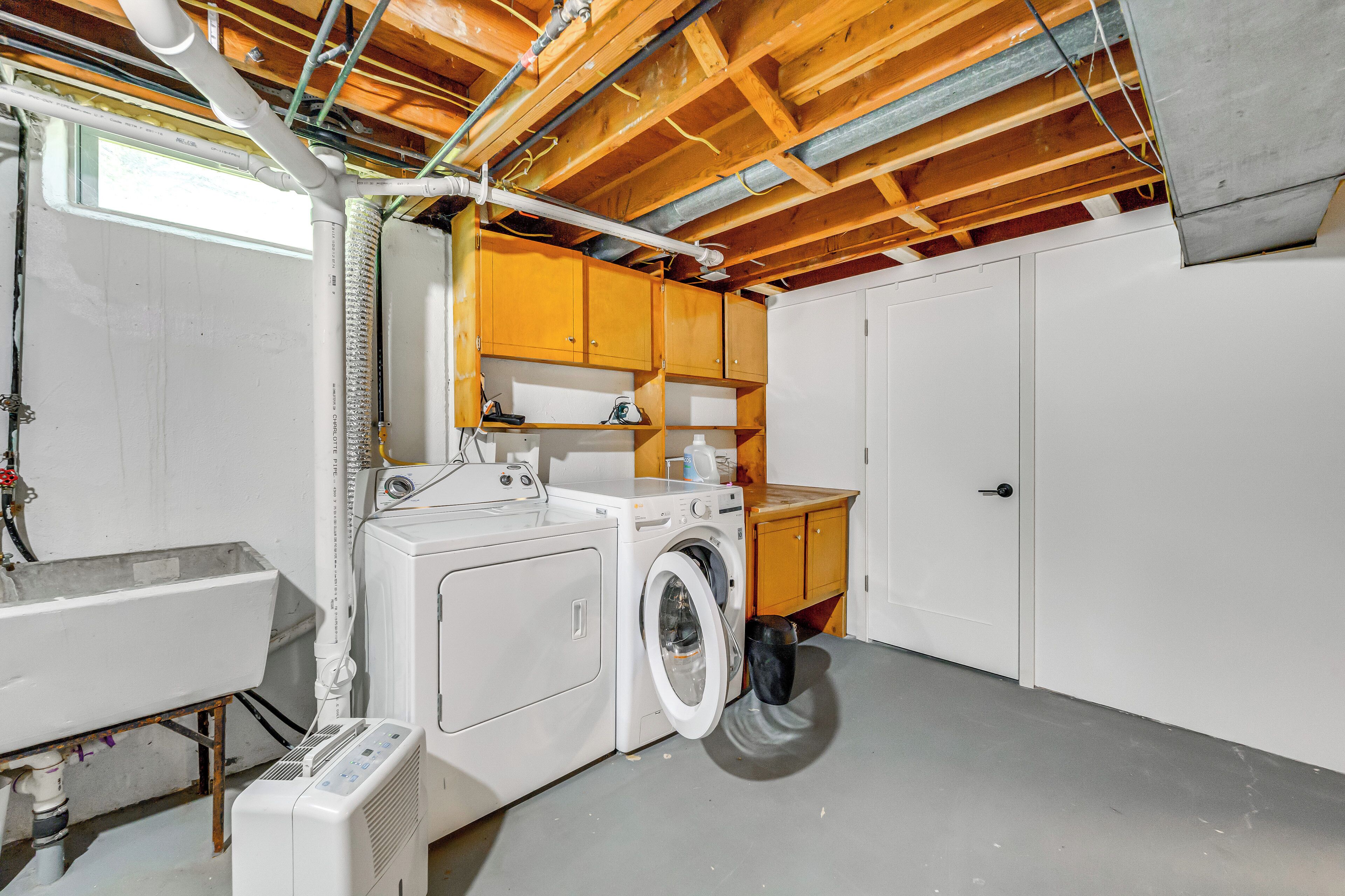 A laundry room with a washing machine, dryer, and a sink.