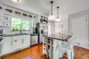 Une cuisine moderne avec des meubles blancs, des appareils en acier inoxydable et un plancher en bois.