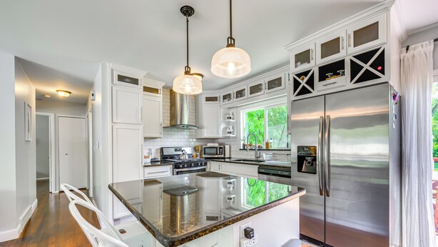 Una cocina moderna con armarios blancos, electrodomésticos de acero inoxidable y una isla grande.