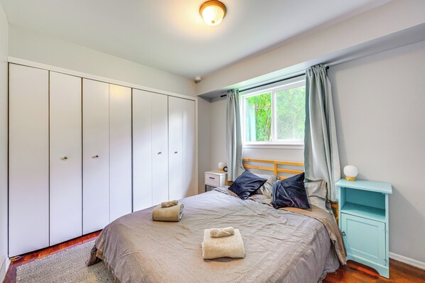 Une chambre à coucher comprenant un lit, une armoire, une table de chevet et une fenêtre.