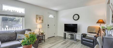 Una sala de estar con sofá, mesa de centro, televisor y una puerta que da a otra habitación.