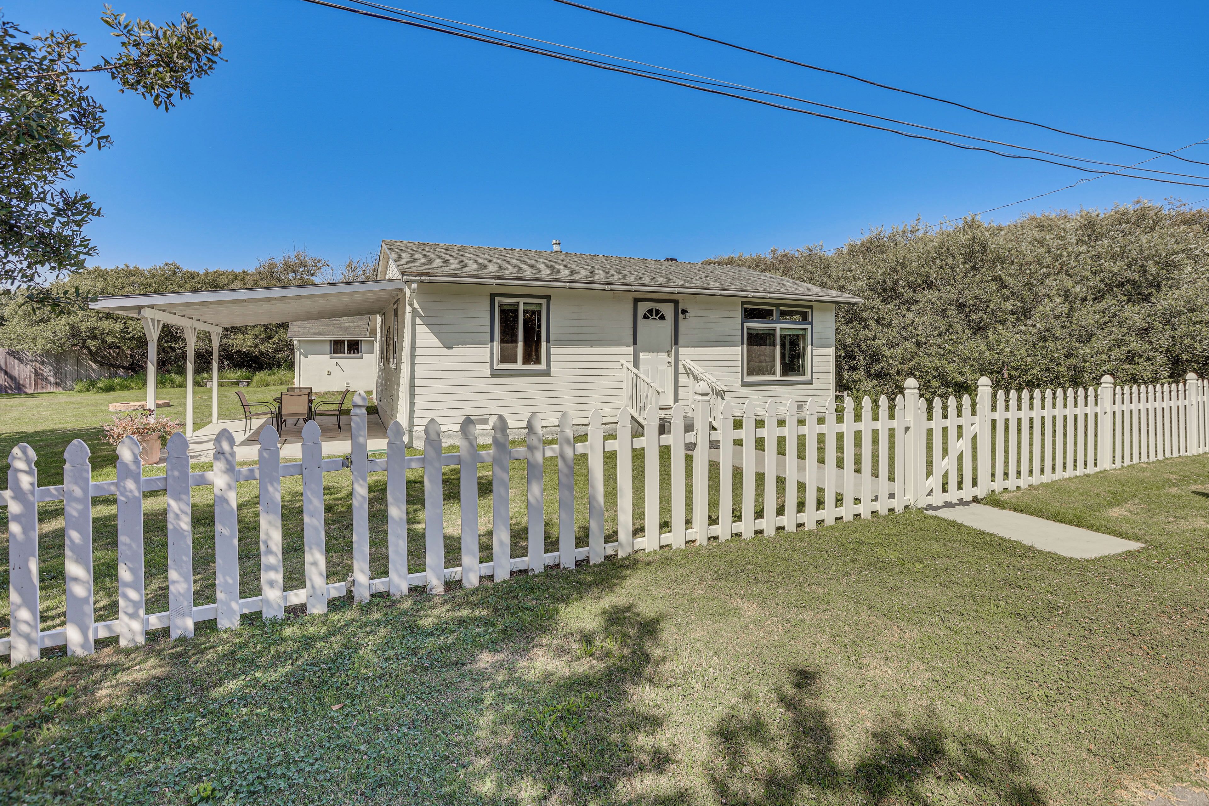 A single-story house with a white picket fence, a covered porch, and a small front yard.