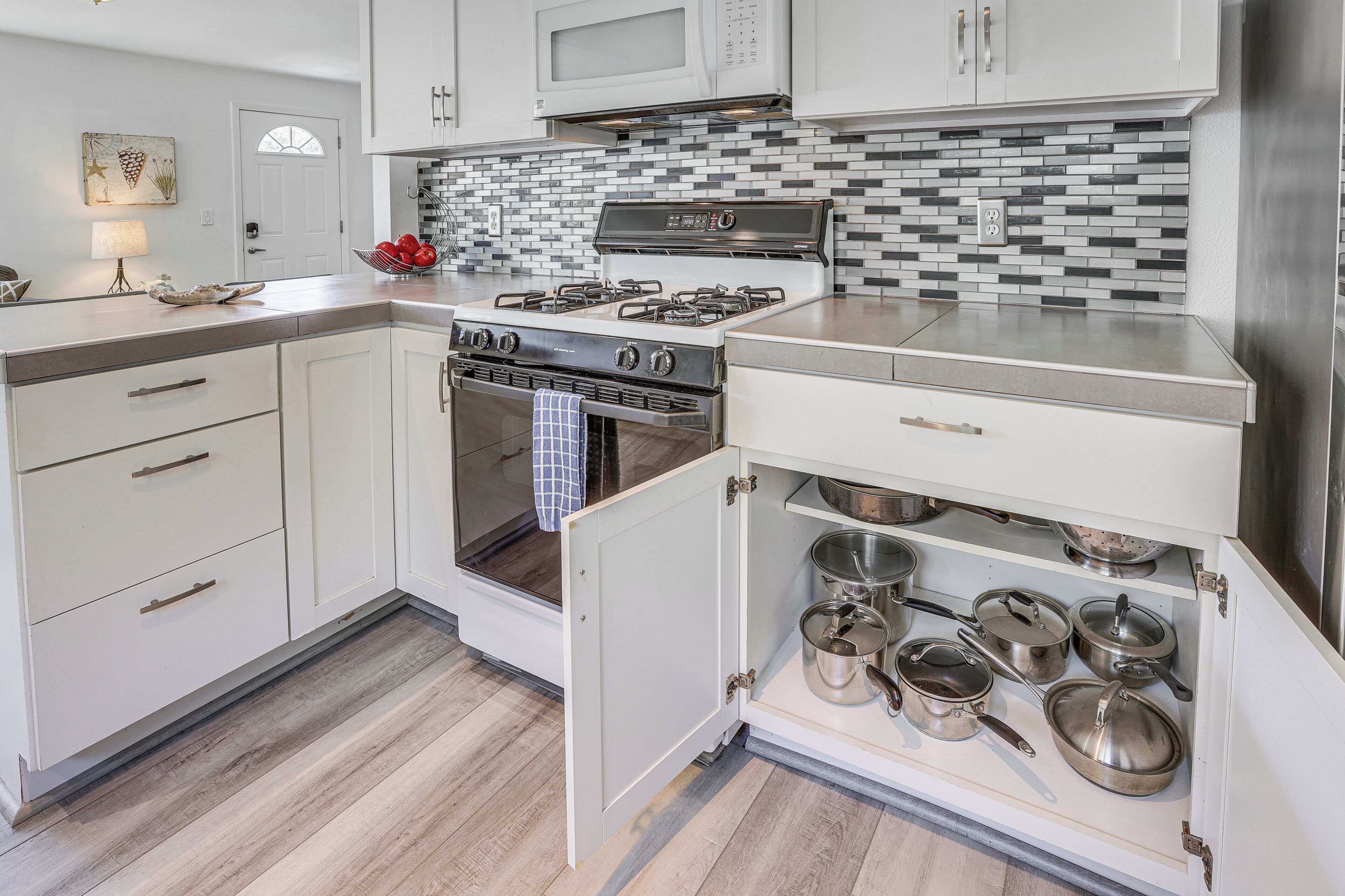 A modern kitchen with white cabinetry, a stainless steel stove, and a tiled backsplash.