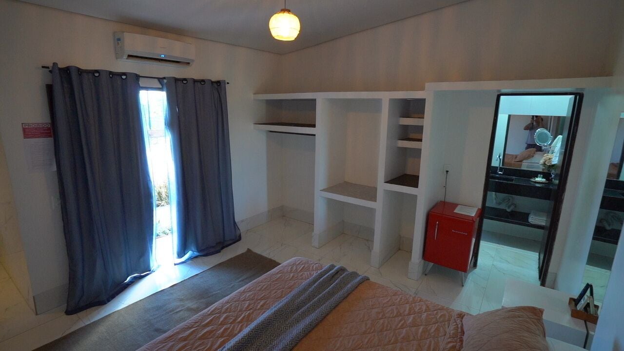 Une chambre à coucher avec un lit, une armoire, un miroir et un meuble rouge.