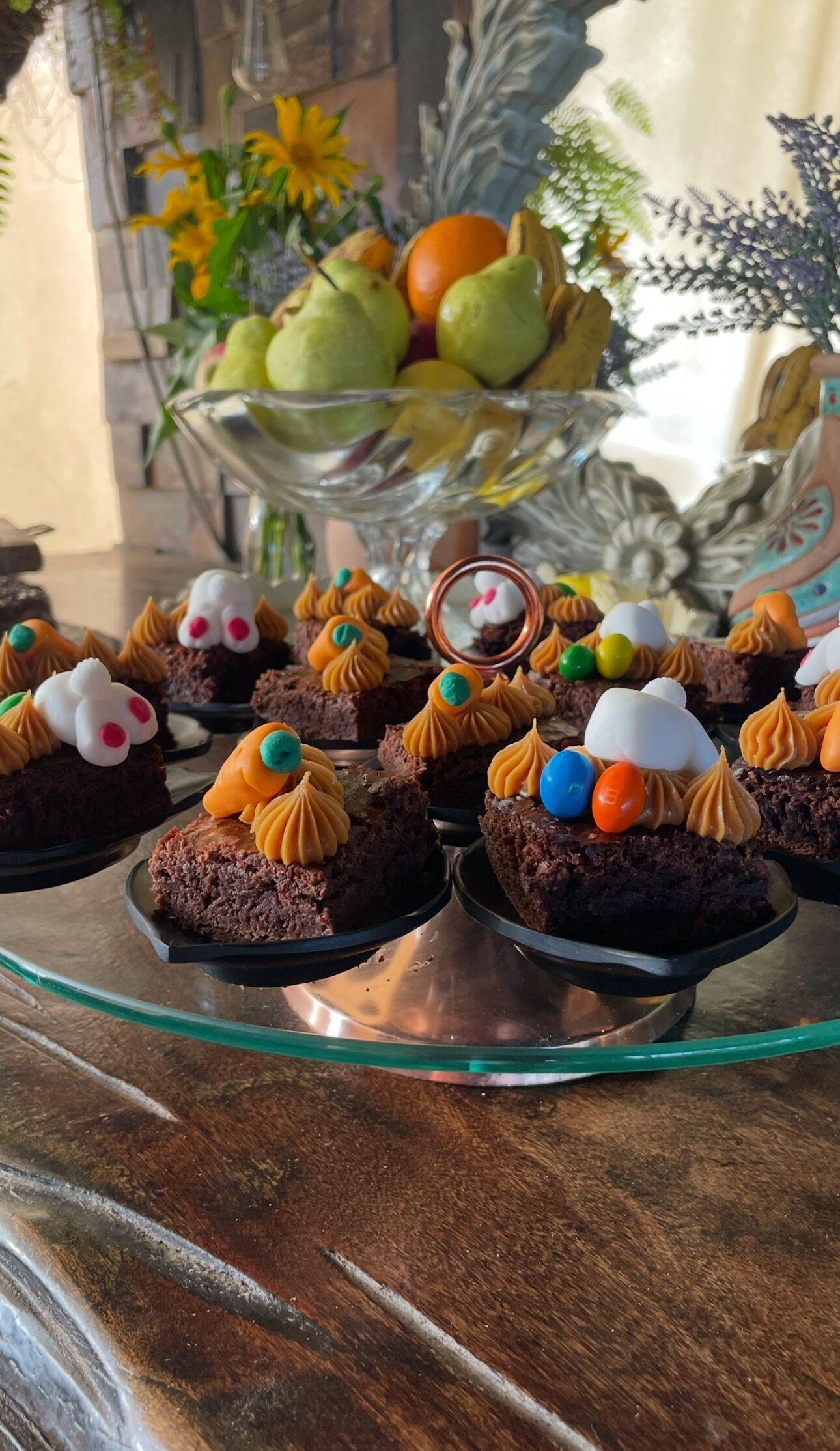 Uma mesa com sobremesas, incluindo cupcakes, sobre um suporte de vidro.