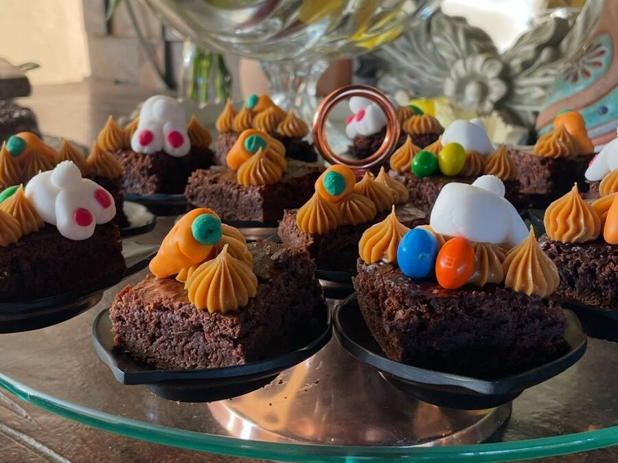 Uma mesa com sobremesas, incluindo cupcakes, sobre um suporte de vidro.