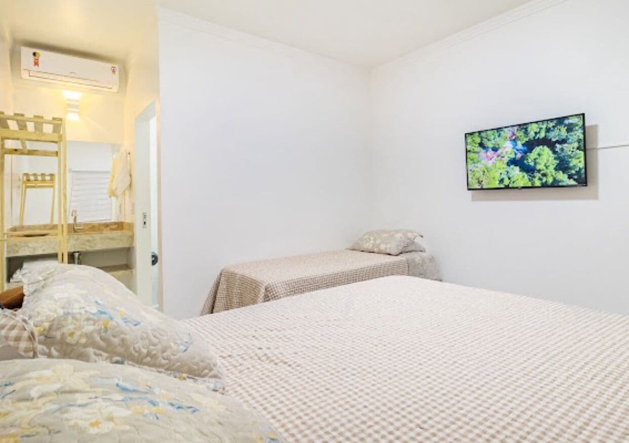 Une chambre avec deux lits, un téléviseur fixé au mur et une échelle en bois.