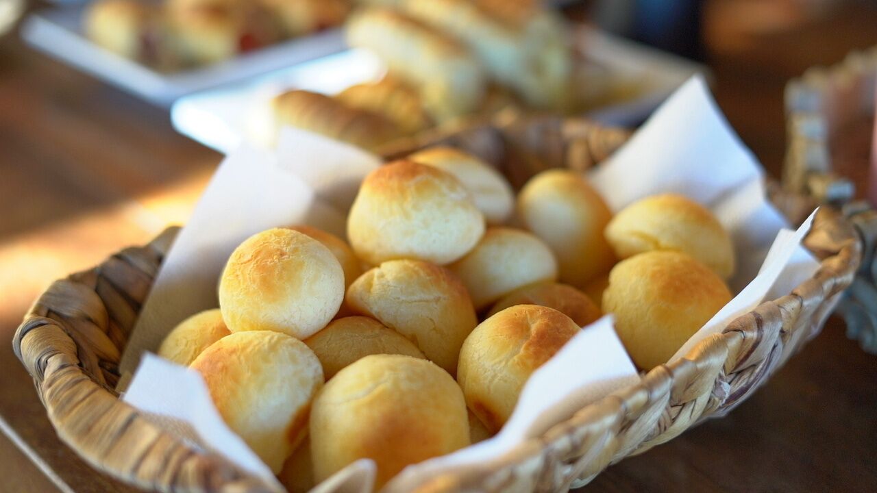 A basket filled with round, golden-brown bread rolls.
