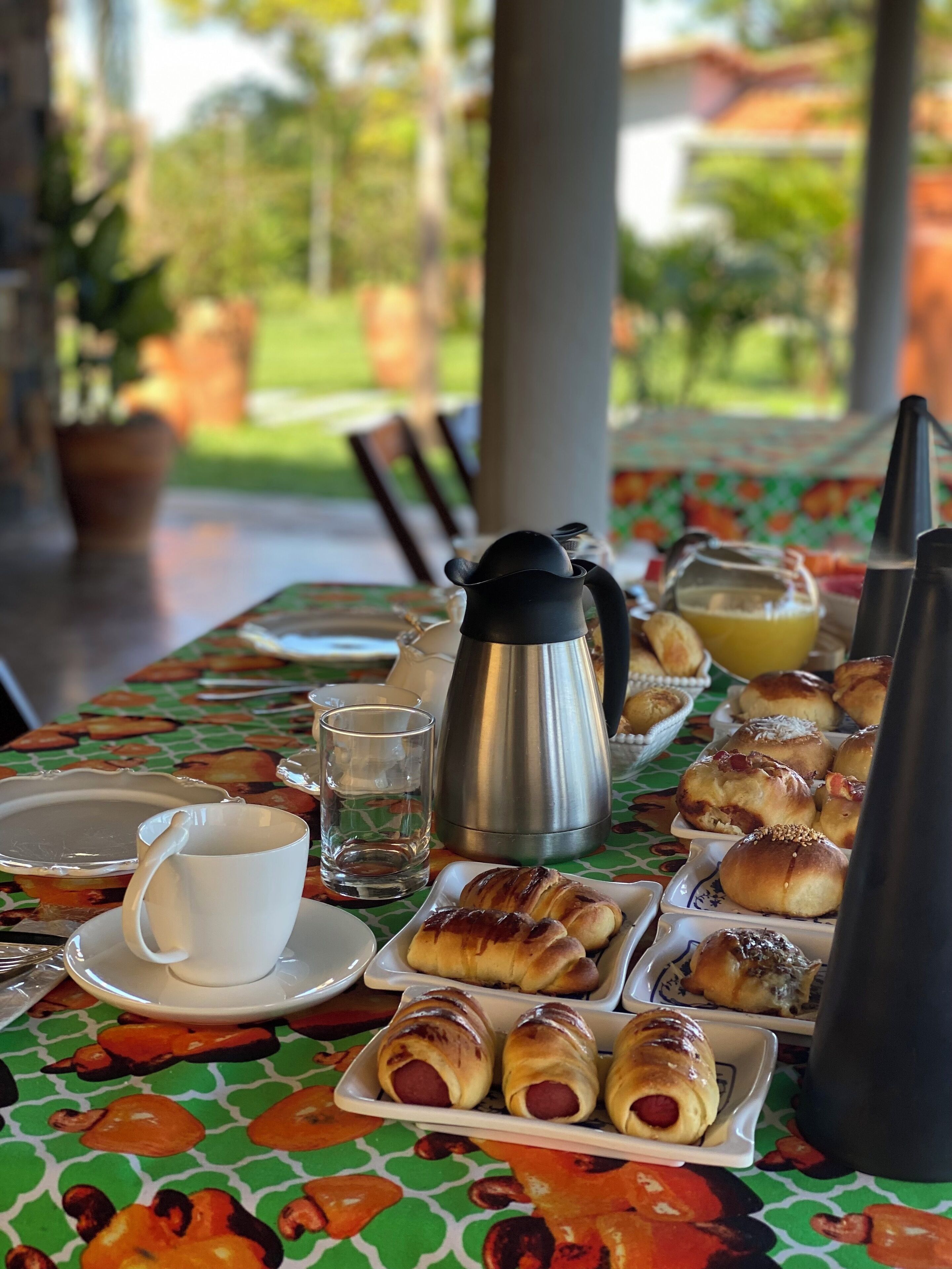 A breakfast table with pastries, a coffee pot, and a cup.
