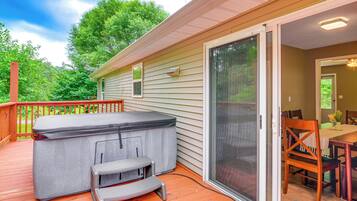 A deck with a hot tub, a covered table, and a sliding glass door leading to a dining area.