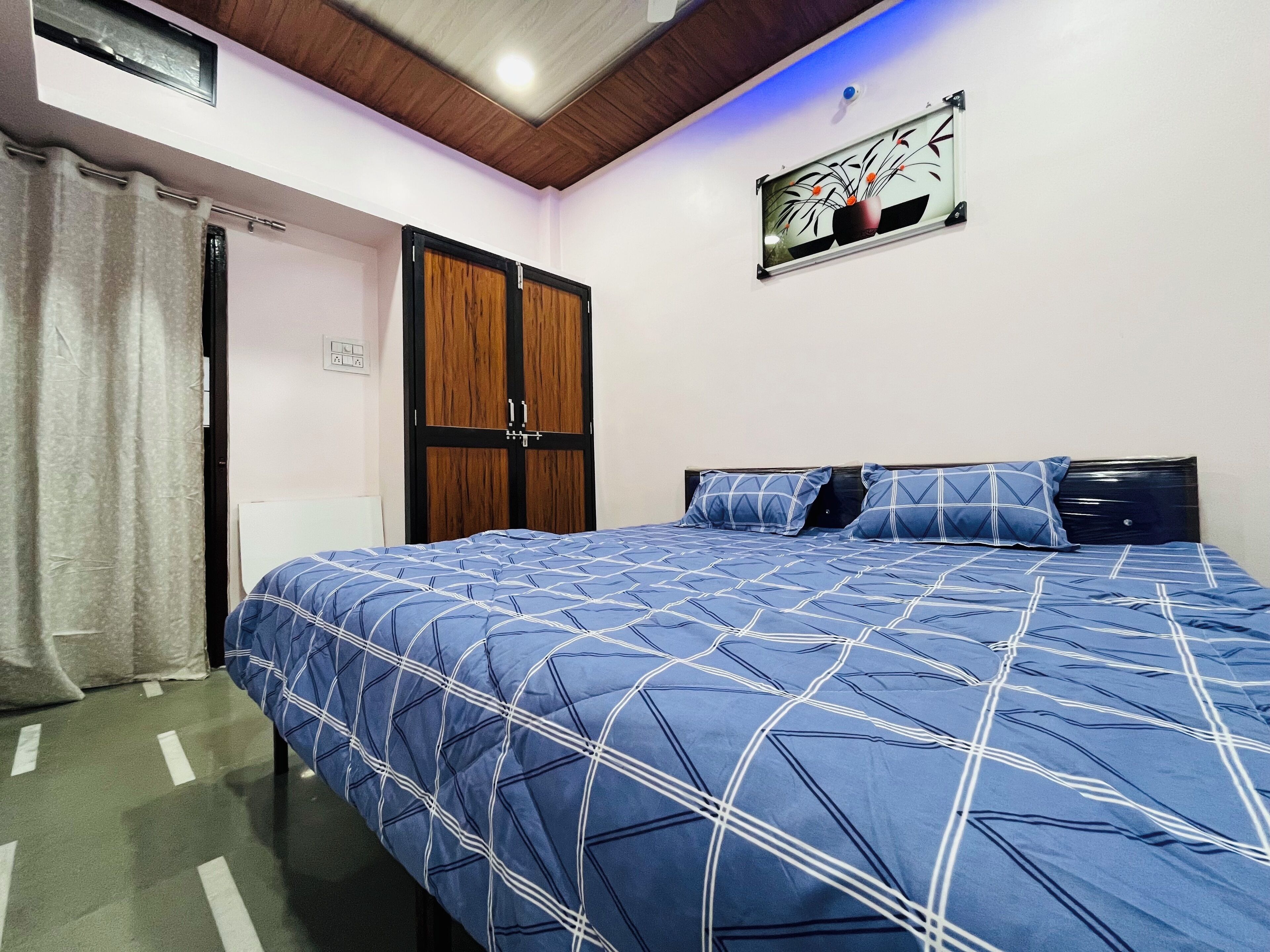A bedroom with a bed, a wardrobe, a ceiling light, and a wall-mounted artwork.