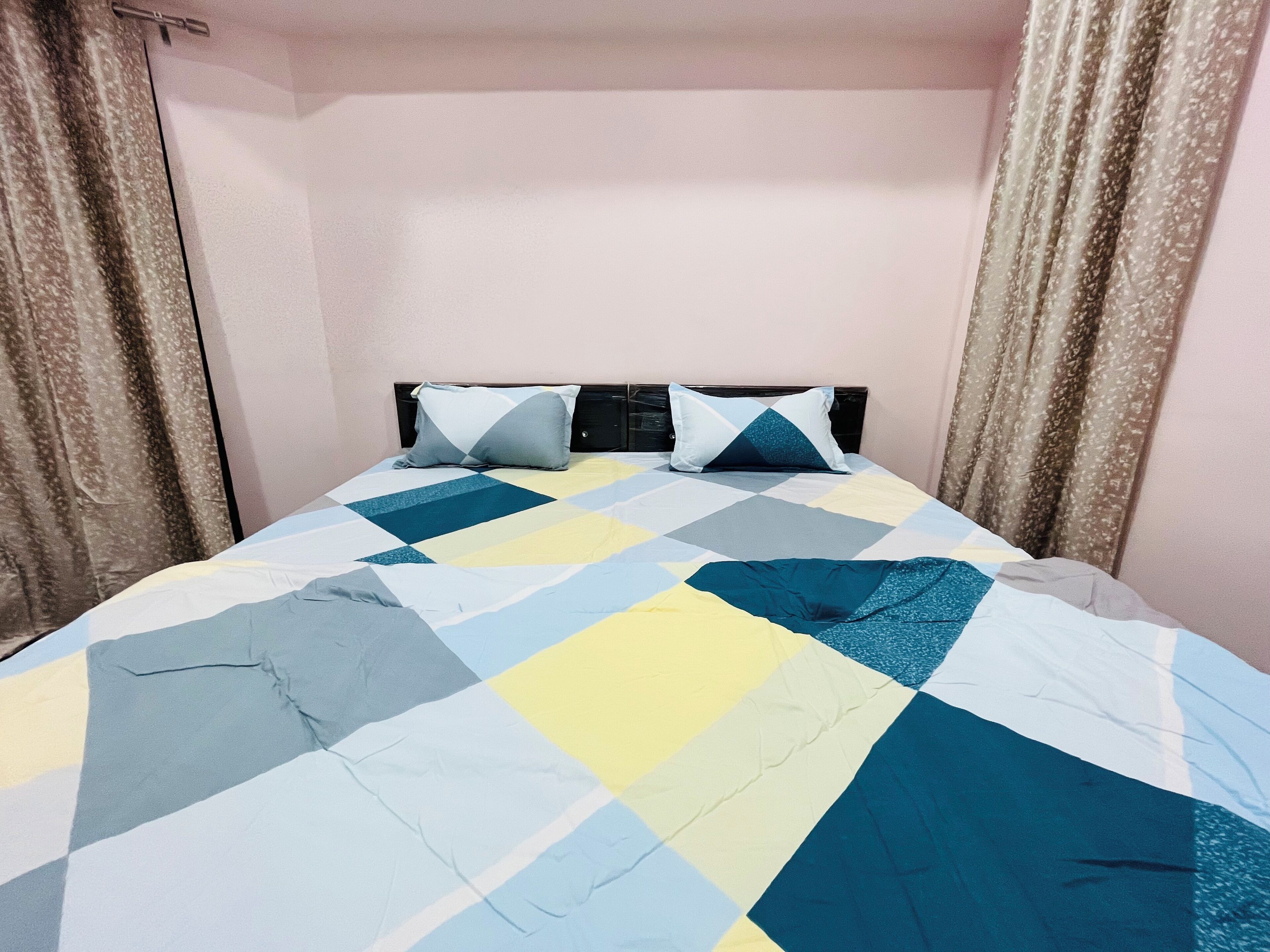 Una cama con una colcha a cuadros en azul, amarillo y gris.