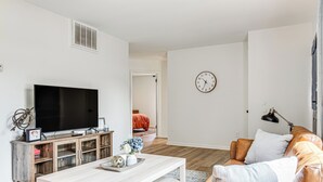 Un salon moderne avec un téléviseur à écran plat, un meuble de rangement en bois, un canapé en cuir et une table à manger.