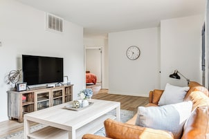Una sala de estar moderna con un televisor de pantalla plana, mueble de entretenimiento de madera, sofá de cuero y una mesa de comedor.
