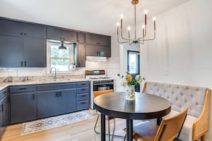 Una cocina moderna con armarios oscuros, una mesa de comedor redonda y un banco tapizado.