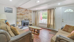 Una sala de estar con chimenea de piedra, sofás de cuero y un ventanal con cortinas.