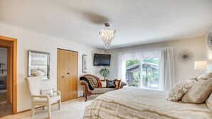 Une chambre à coucher avec un grand lit, une chaise, un téléviseur et un lustre.