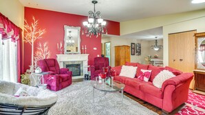 Un salon avec un mur rouge, une cheminée, un canapé rouge et une table basse en verre.