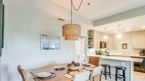 A modern kitchen with white cabinets, a central island, and pendant lighting.