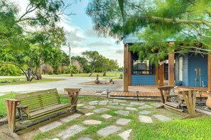 A wooden bench and picnic table in a park area with stone pathways and greenery.