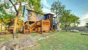 Ein zweistöckiges Haus mit einer Holzterrasse und einer Treppe, die zum oberen Stock führt.