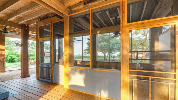 Eine überdachte Veranda mit Holzbalken und großen Fenstern.