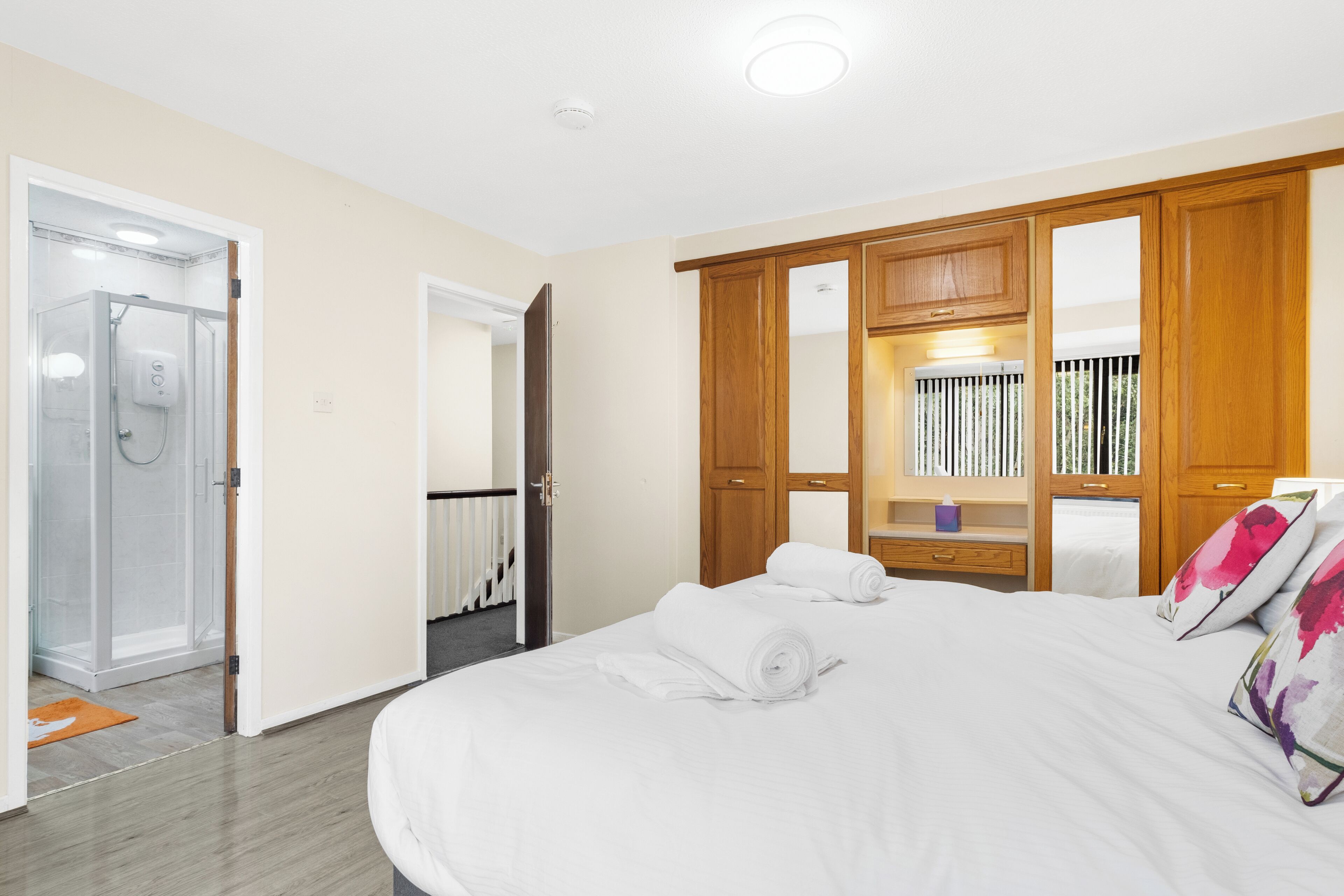 A hotel room with a large bed, wooden wardrobe, and a shower area.