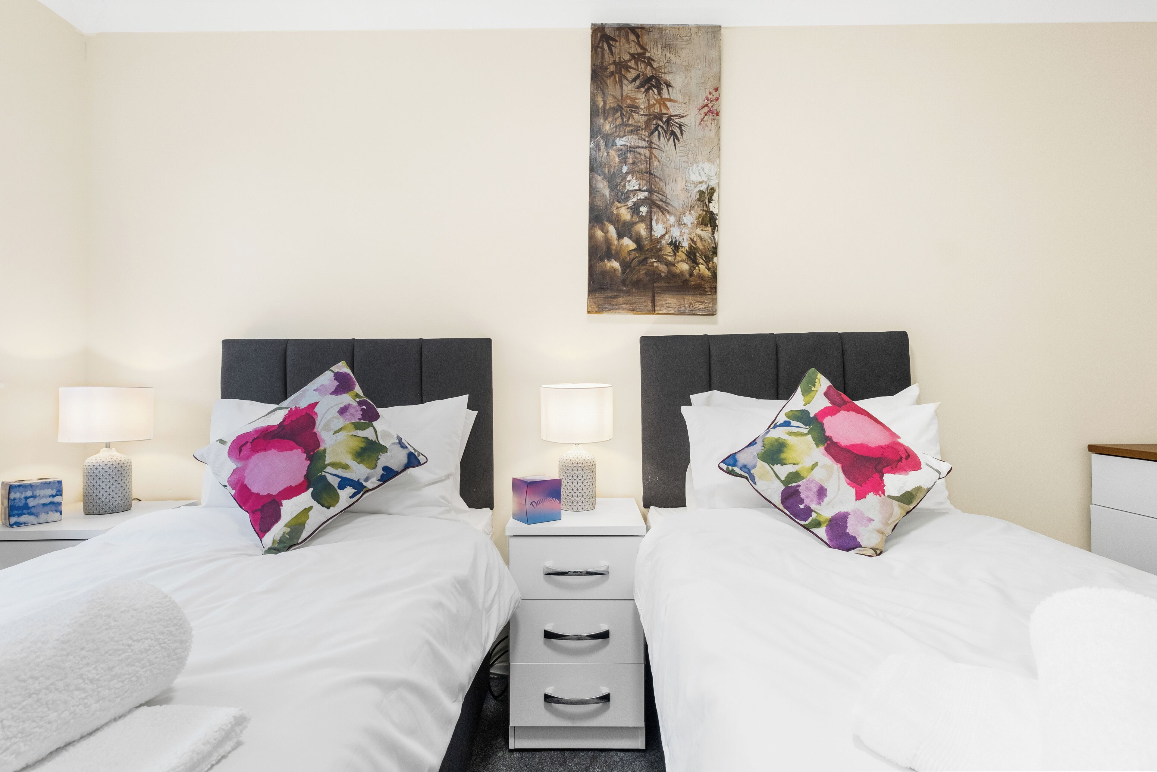 Une chambre d’hôtel avec deux lits, chacun étant équipé d’un oreiller et d’une table de chevet avec une lampe.