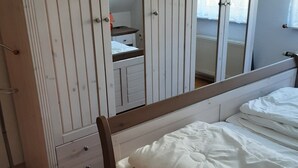 Un dormitori amb un llit, un armari amb mirall i una petita taula de nit.