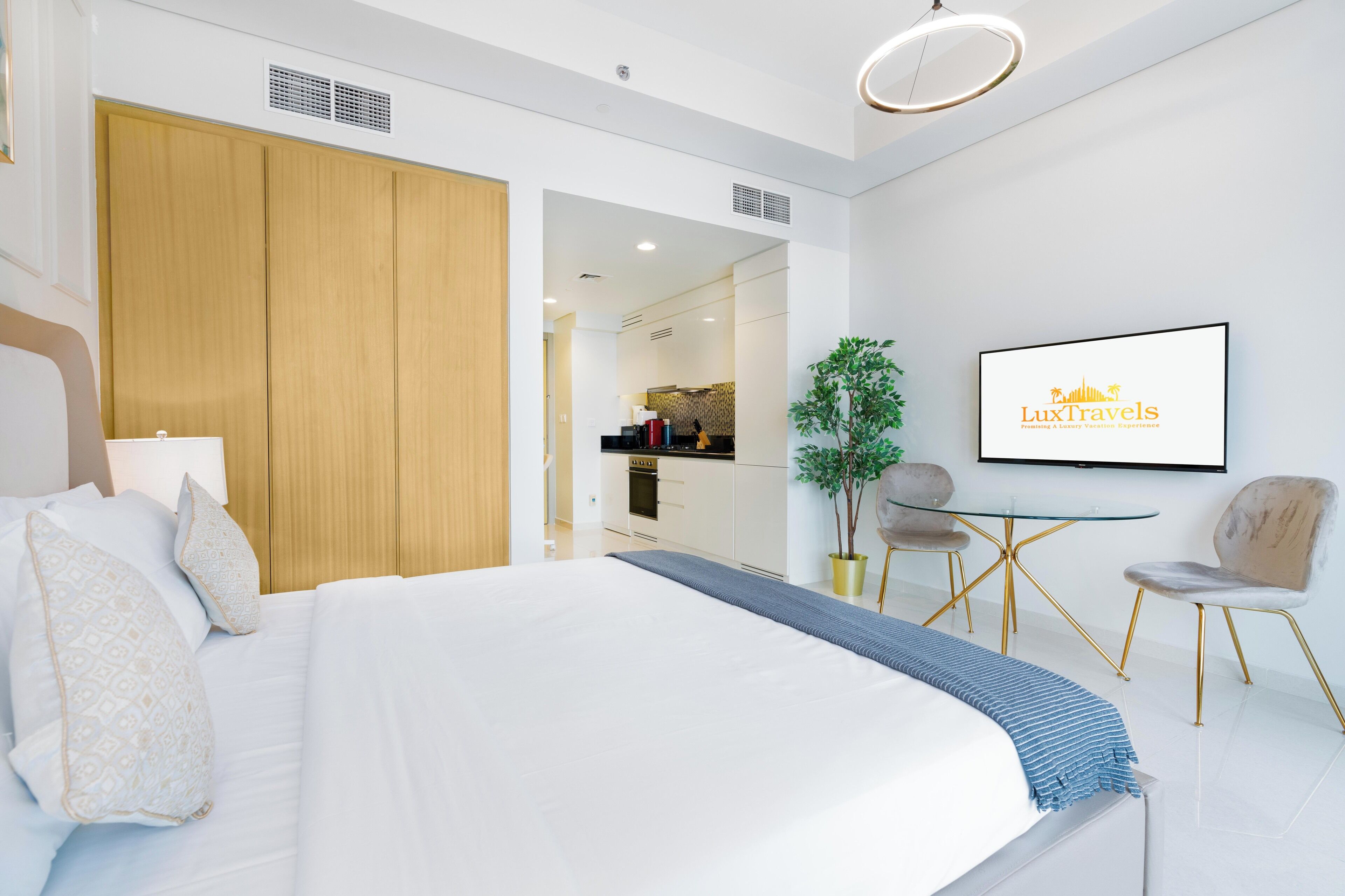 A modern hotel room with a large bed, a desk, and a dining area.