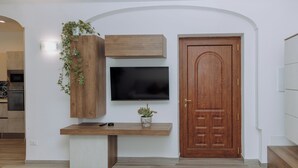 Une cuisine moderne dotée d’un téléviseur encastré, de meubles en bois et d’une plante.