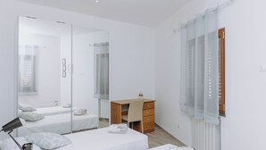 Une chambre d’hôtel moderne avec deux lits, un bureau en bois, un miroir et une fenêtre avec des rideaux.