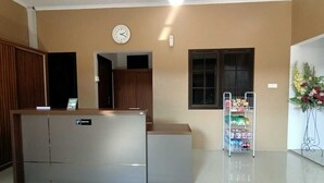 Un espace d’accueil comprenant un comptoir de réception, une horloge, une fenêtre et un distributeur automatique.
